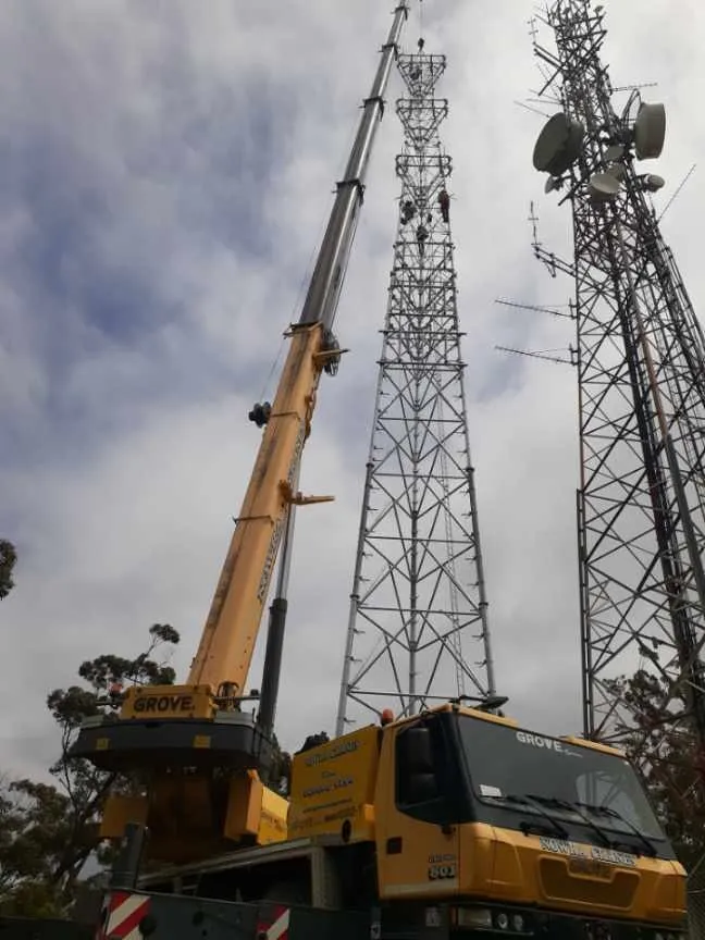 Crane working beside communications towers