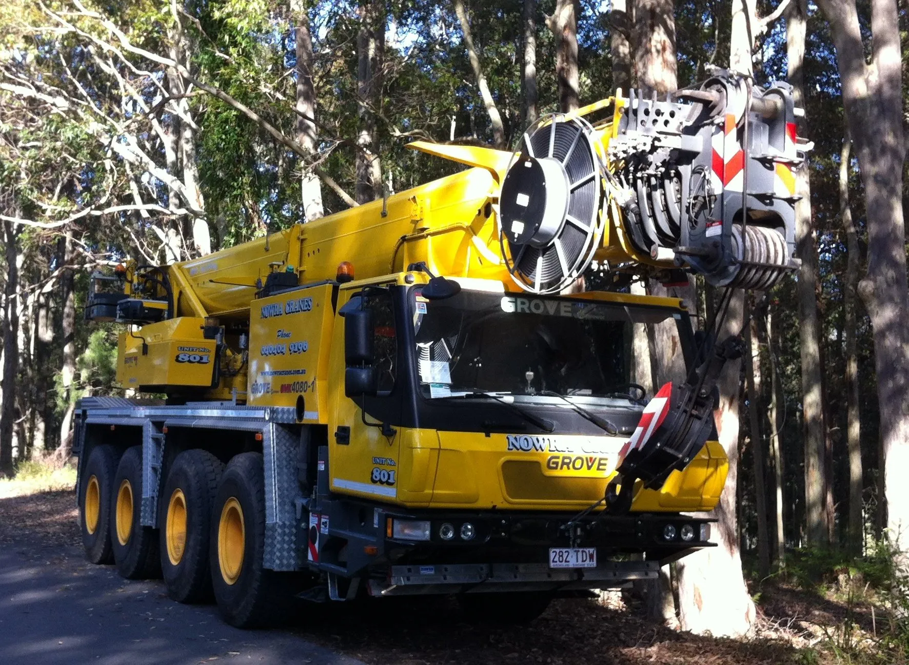 All-terrain mobile crane parked on a bush road, boom stowed