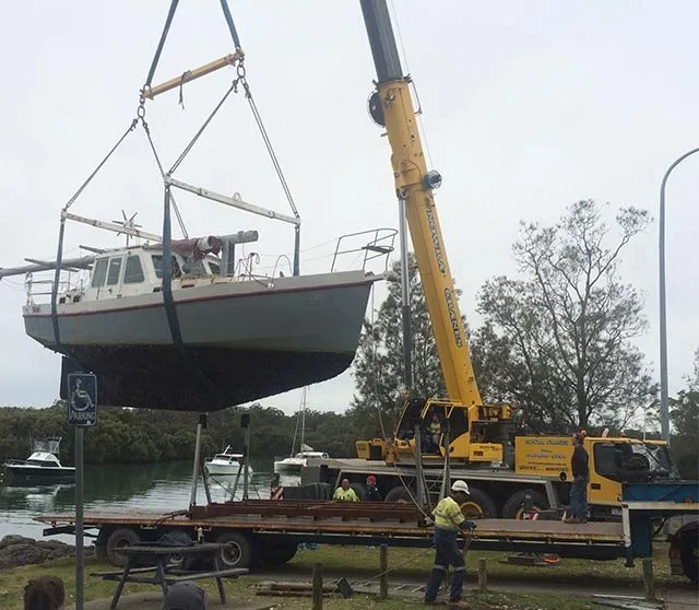 Motor cruiser lifted at a river ramp