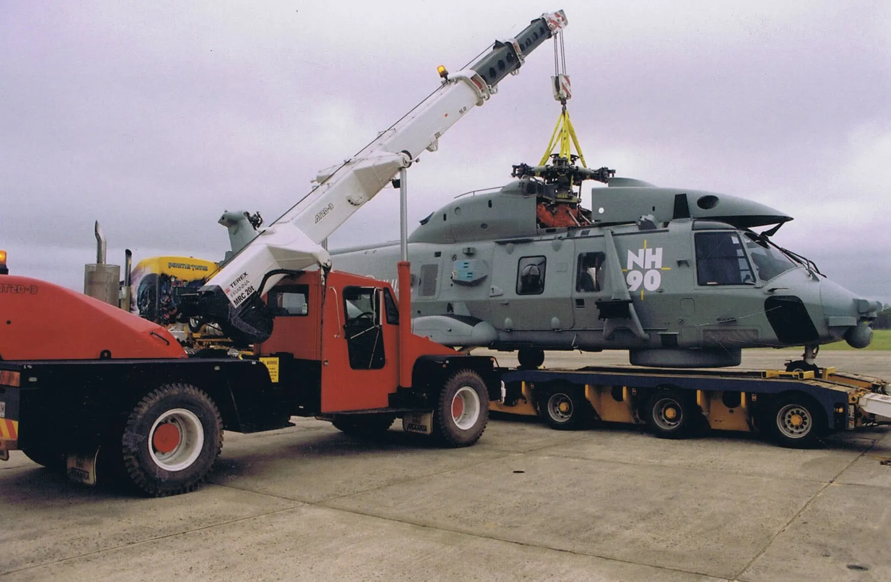 Crane loading a navy helicopter onto a low loader