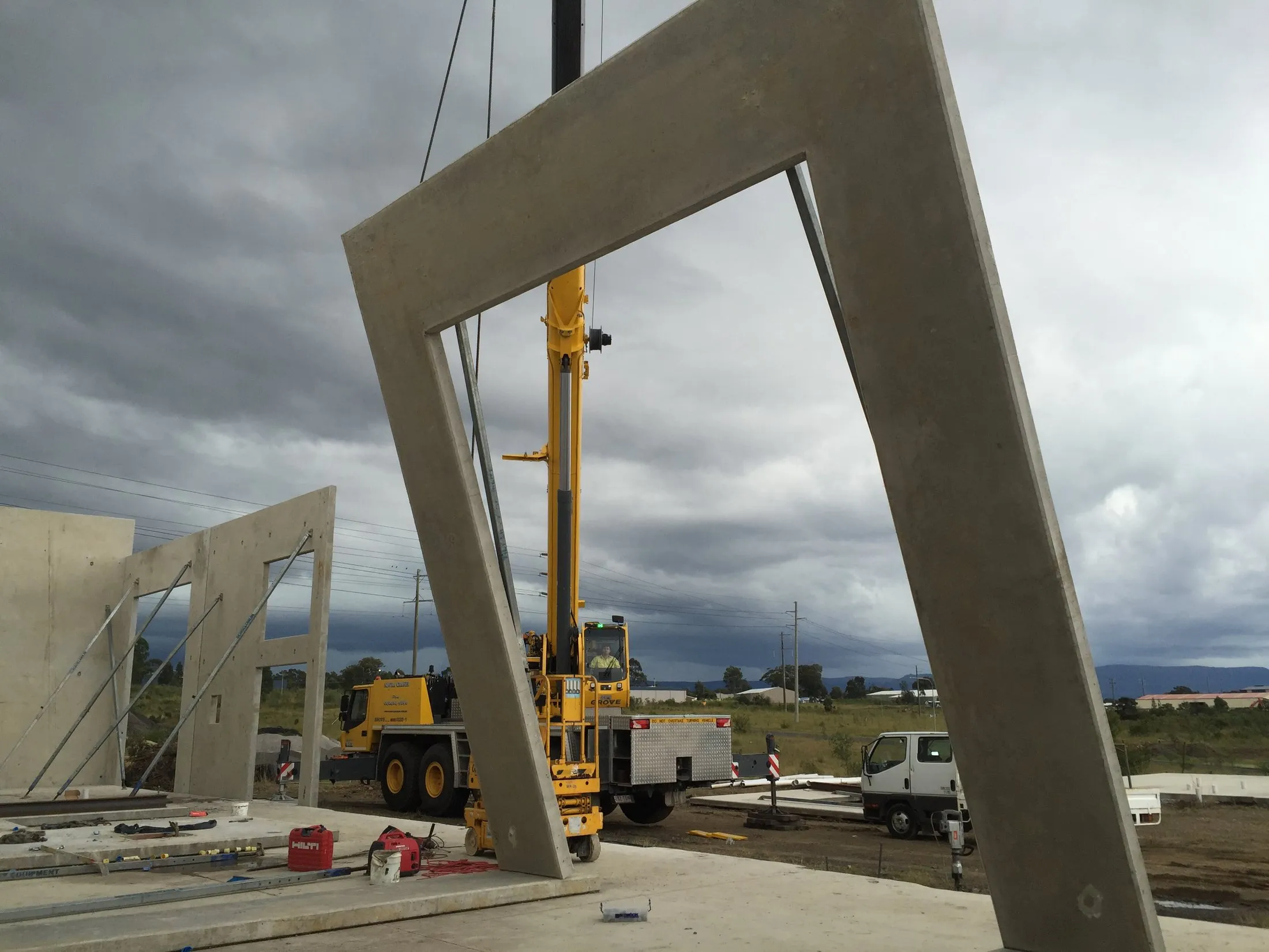 Precast concrete portal frame lifted into place under a stormy sky