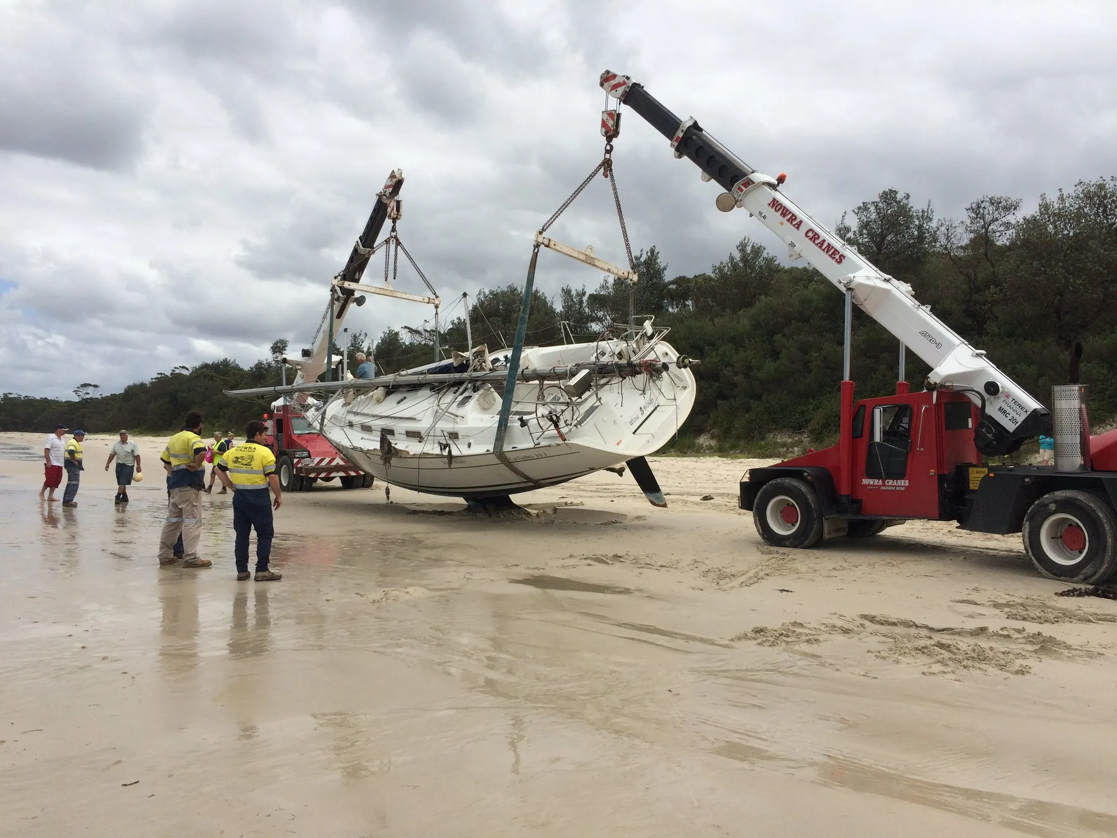 Two cranes recovering a yacht from the beach